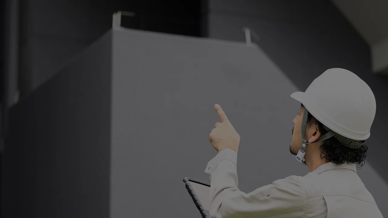 ヘルメットを被った作業員が、施工後の看板を指差して安全点検を行うアフターワーク。